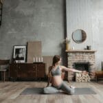Ciężarna kobieta ćwicząca jogę w salonie z psem obok