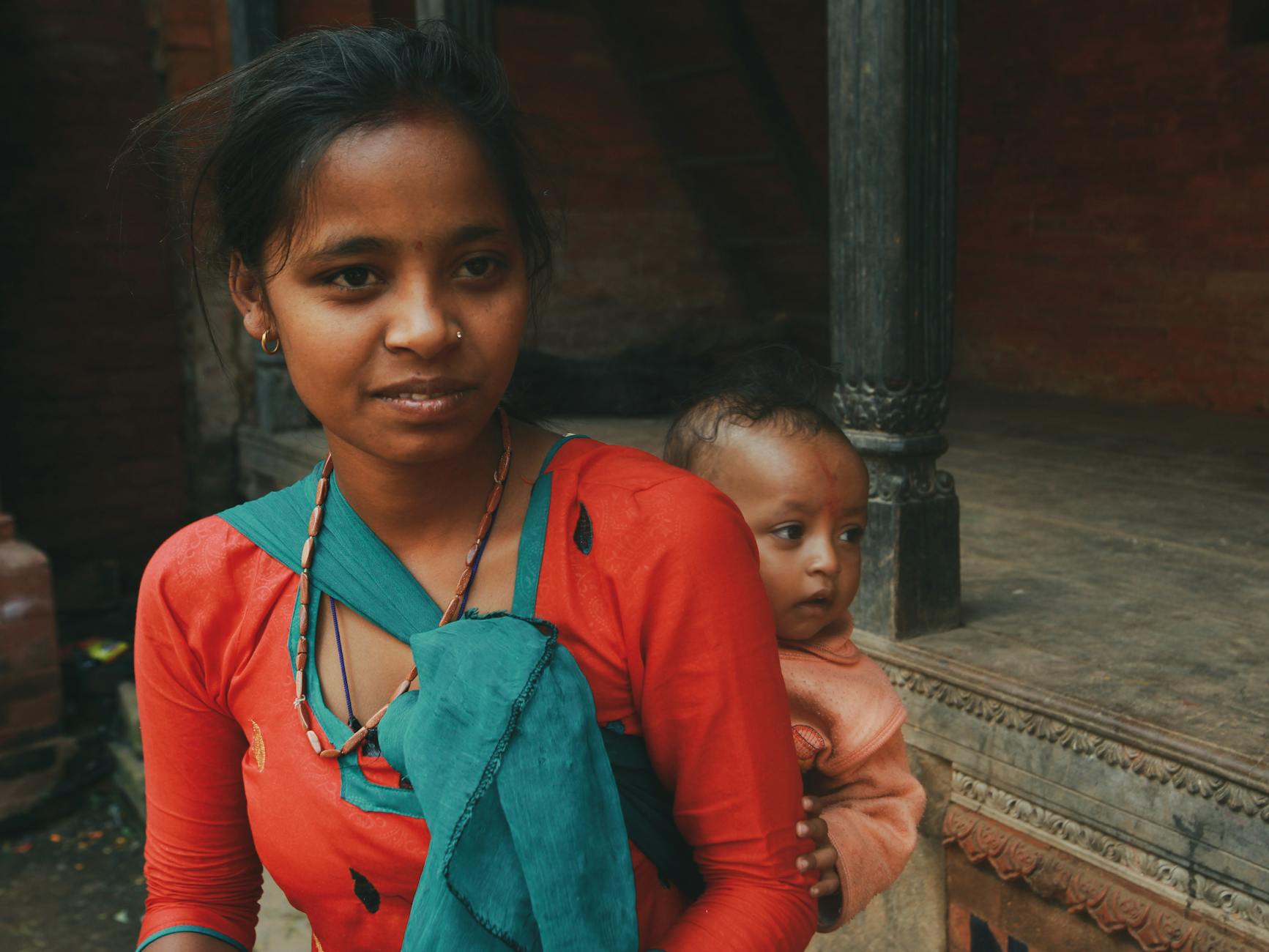 Młoda mama w tradycyjnym stroju nosi dziecko w chuście