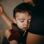 Śpiące dziecko przytulone do mamy na domowej kanapie