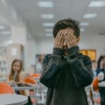Jak rozpoznać wypalenie szkolne u dziecka i co zrobić, zanim problem urośnie Chłopiec w klasie zasłania twarz dłońmi z powodu szkolnego stresu