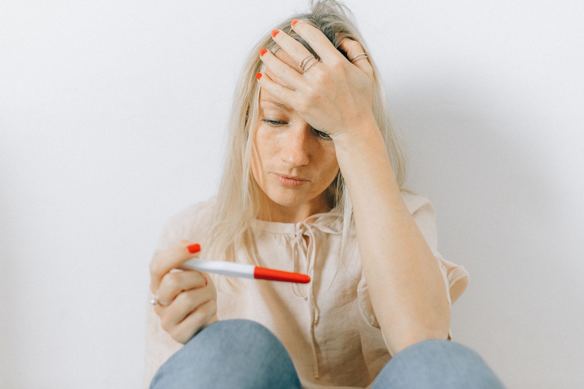 Czy stres w ciąży naprawdę szkodzi dziecku? Fakty Zaniepokojona kobieta trzyma test ciążowy i patrzy na niego z niepewnością